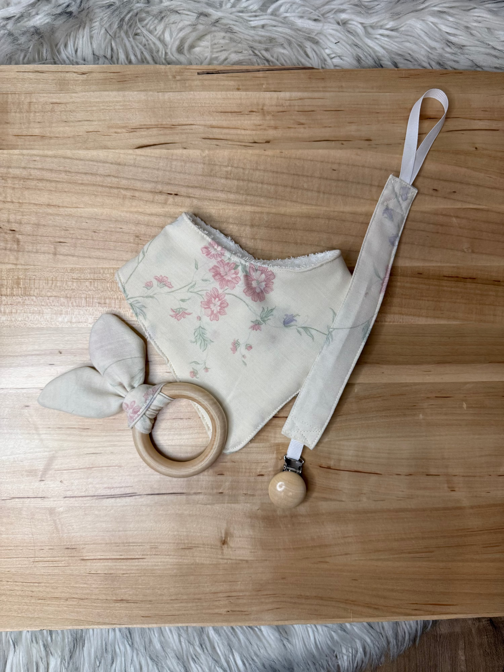 Floral-patterned baby mask with wooden ring and strap on a wooden surface